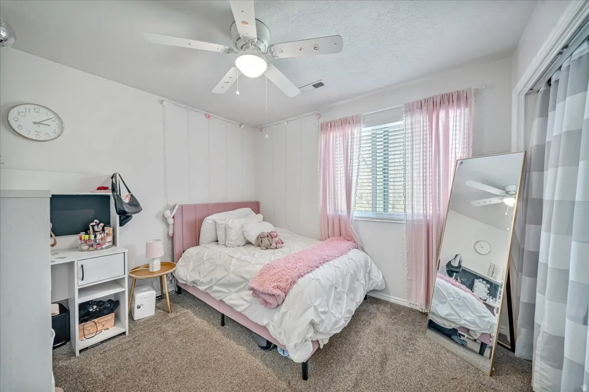 Bedroom with carpet flooring, a ceiling fan, and a textured ceiling