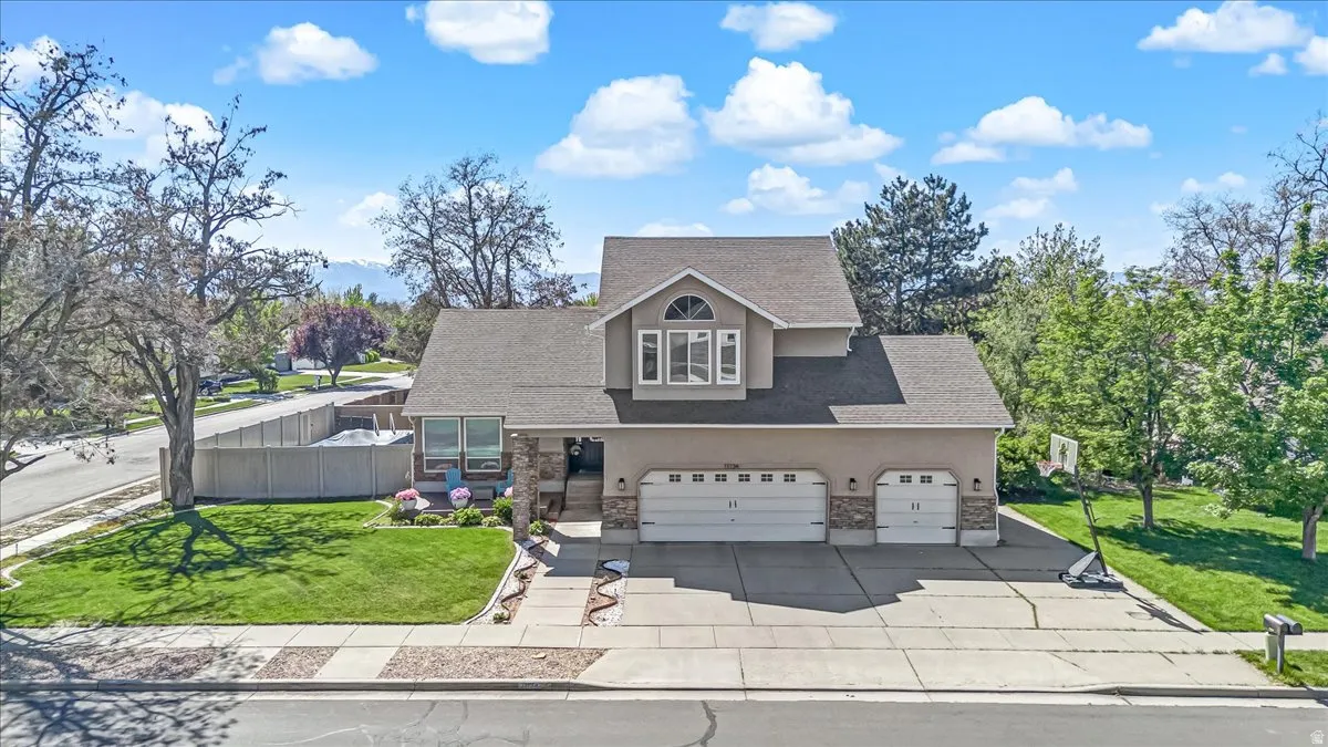 Traditional-style home featuring stone siding, roof with shingles, a garage, and concrete driveway