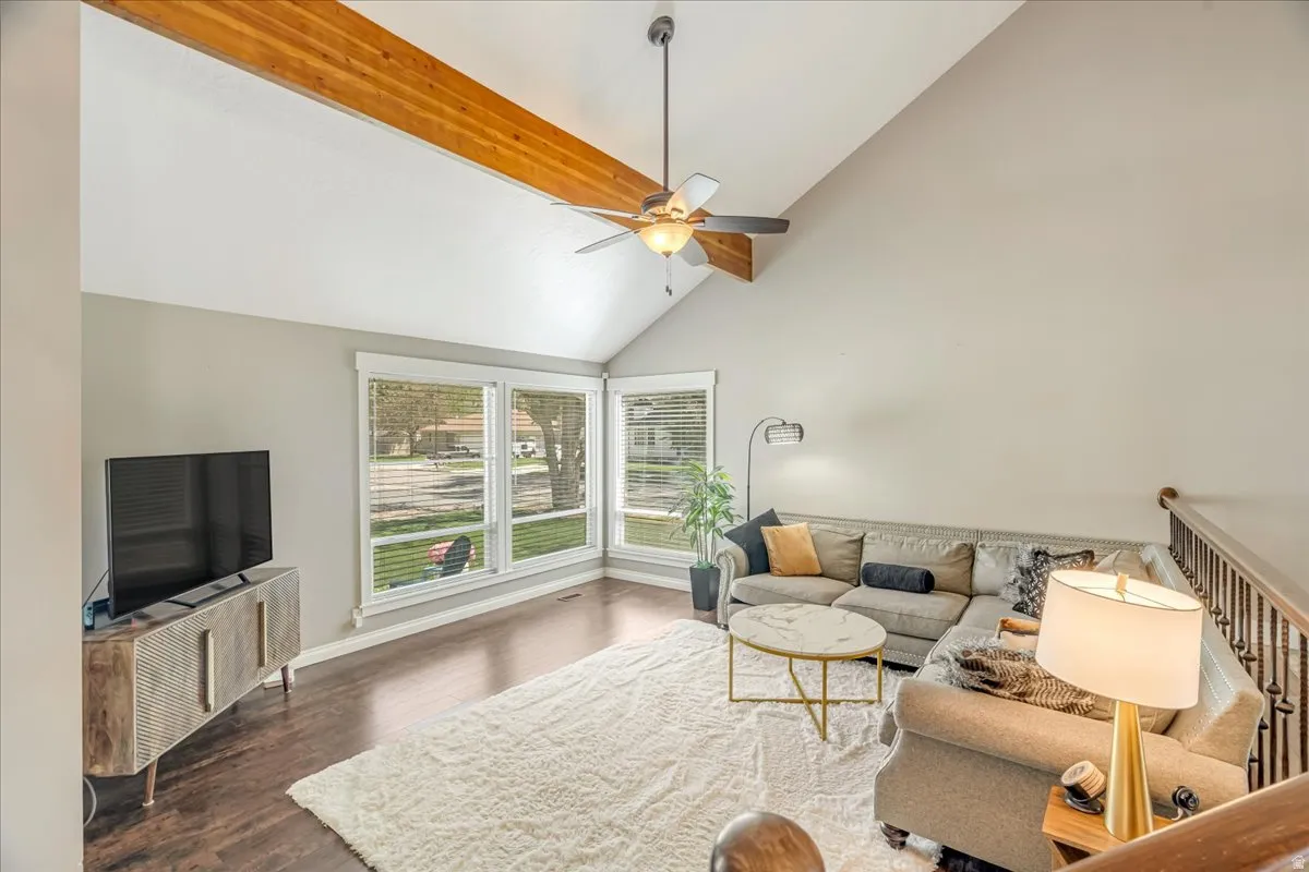 Living room featuring vaulted ceiling, dark wood finished floors, and a ceiling fan