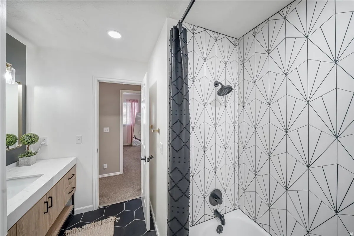 Full bath featuring shower / tub combo with curtain, vanity, dark tile patterned floors, dark colored carpet, and recessed lighting