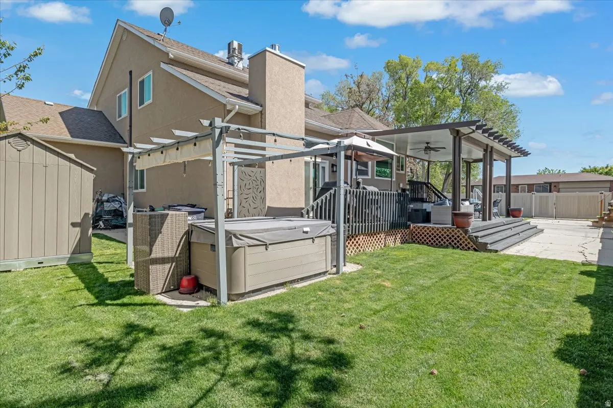 Rear view of house with a shed, a pergola, a ceiling fan, a patio, and a hot tub