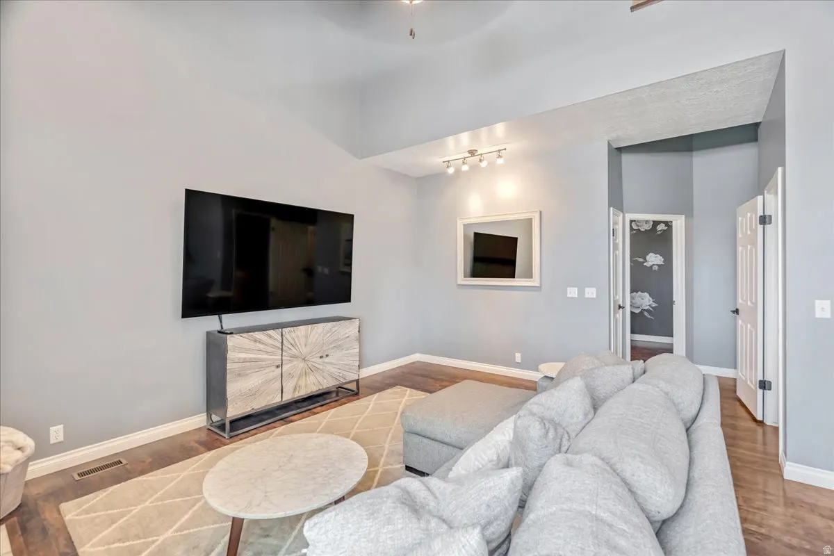 Living room featuring wood finished floors, a ceiling fan, and rail lighting