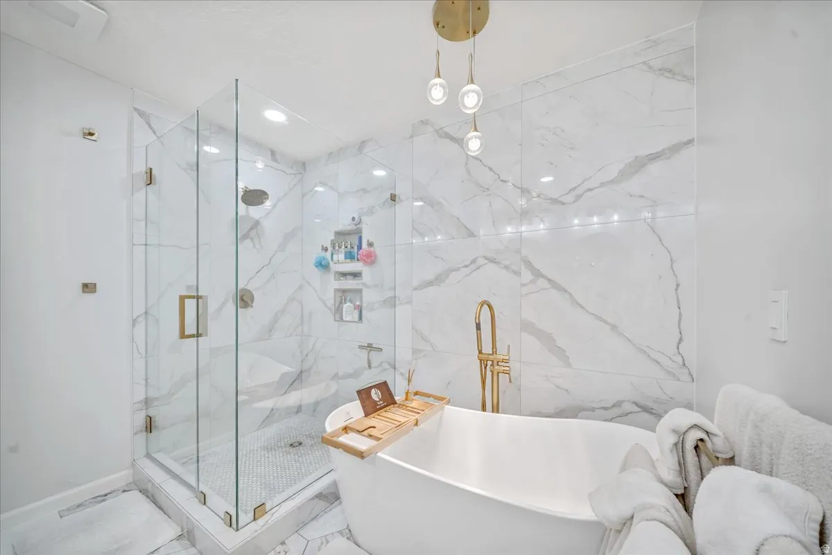 Bathroom featuring a freestanding bath, a marble finish shower, marble finish flooring, and recessed lighting