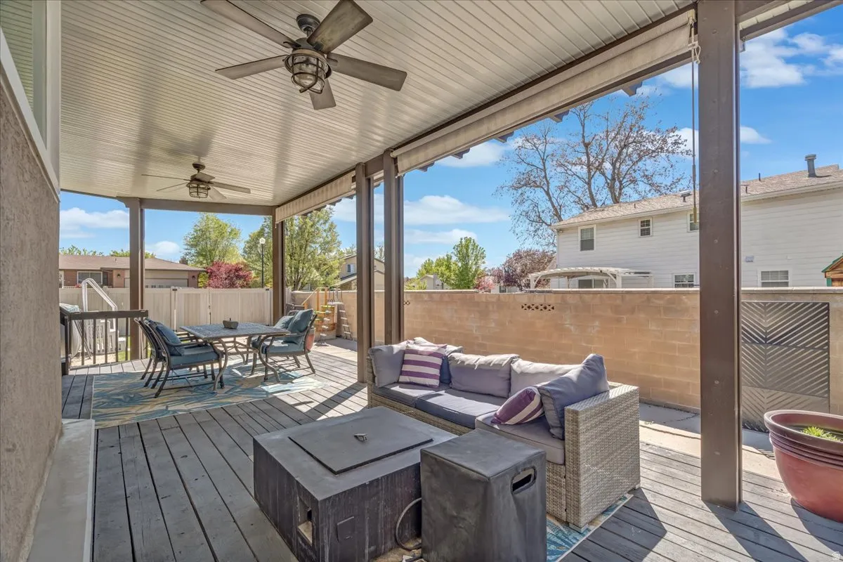 Wooden deck featuring ceiling fan, an outdoor living / dining area, and a fenced backyard