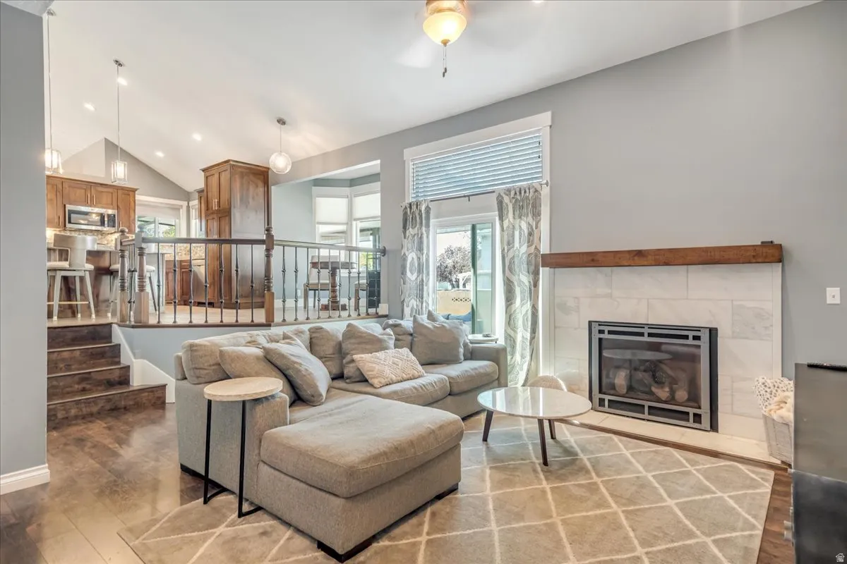 Living area with recessed lighting, vaulted ceiling, hardwood / wood-style flooring, ceiling fan, and a tiled fireplace
