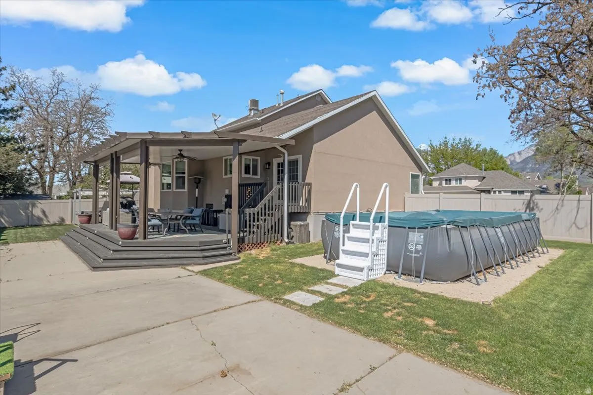 Back of house with a fenced backyard, stucco siding, ceiling fan, and a wooden deck