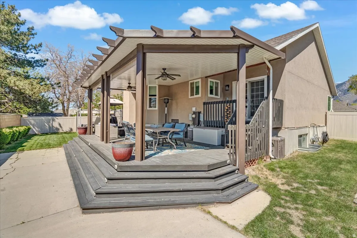 Rear view of house featuring ceiling fan, a fenced backyard, outdoor dining area, and a wooden deck