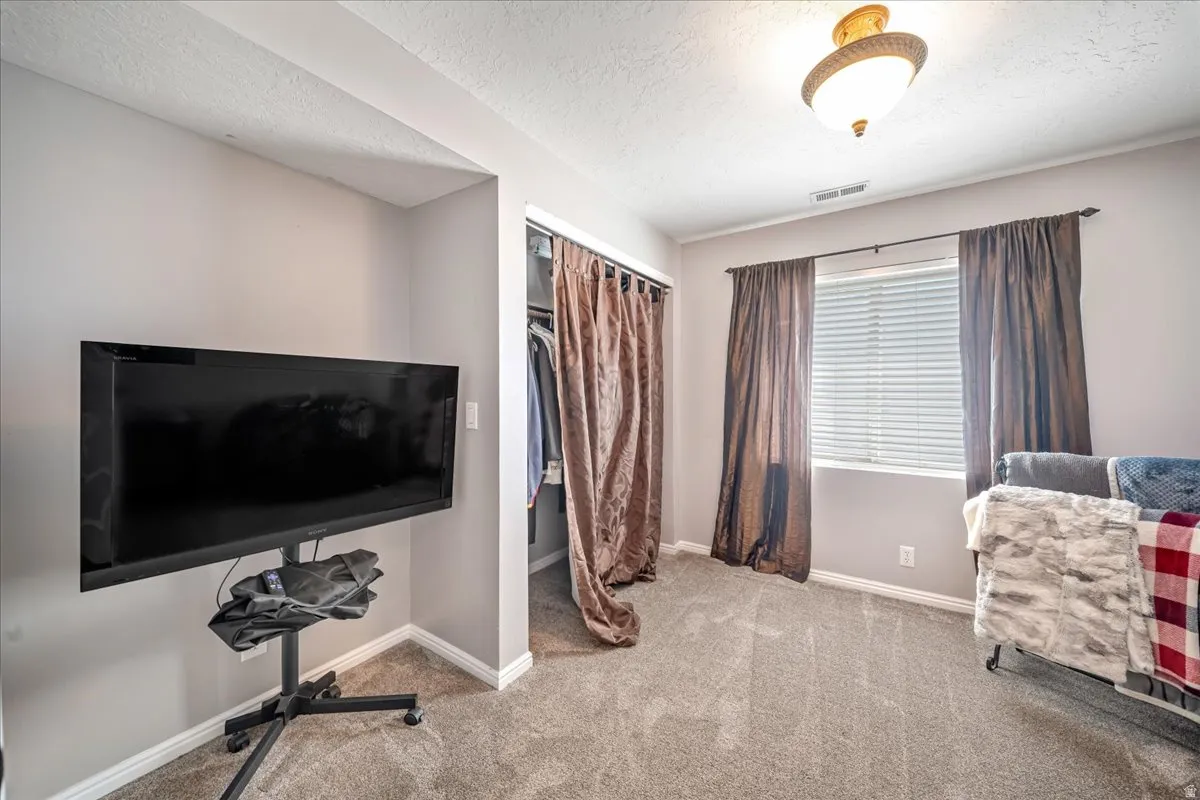 Bedroom with light carpet, a closet, and a textured ceiling