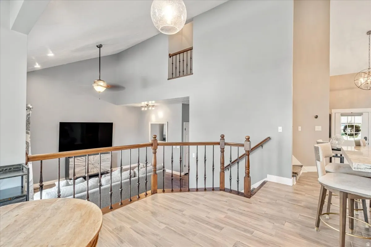 Living room featuring a chandelier, light wood finished floors, vaulted ceiling, and ceiling fan