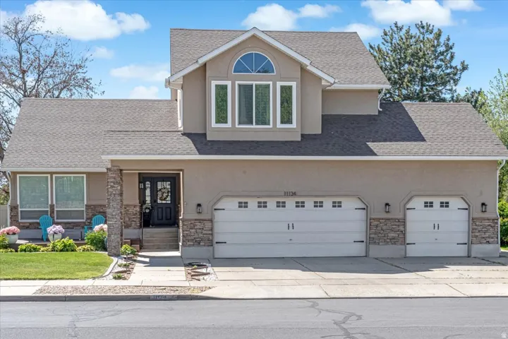 View of front of house featuring stone siding and a shingled roof