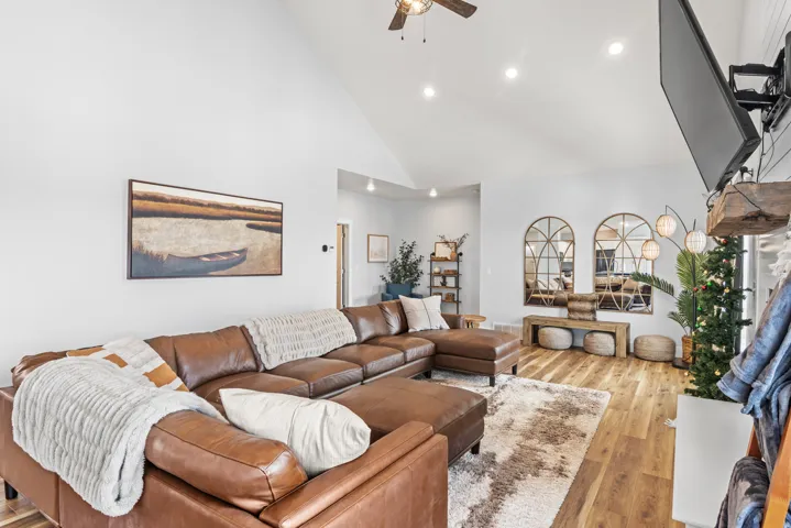 Living room with a ceiling fan, hardwood / wood-style flooring, recessed lighting, and lofted ceiling