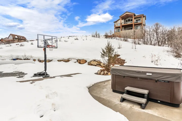 Yard layered in snow with a hot tub