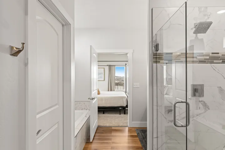 Full bathroom with light wood-style flooring, a marble finish shower, connected bathroom, and a garden tub