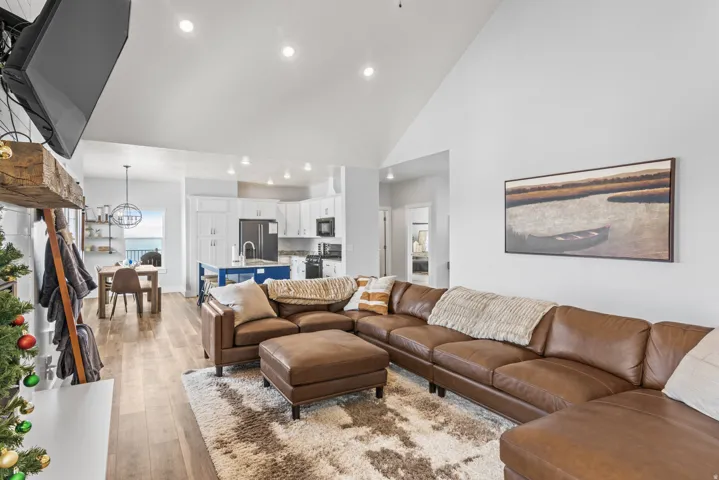 Living area with light wood-style floors, vaulted ceiling, and a chandelier
