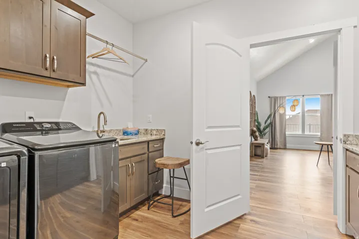 Laundry room featuring cabinet space, light wood-style flooring, vaulted ceiling, and separate washer and dryer