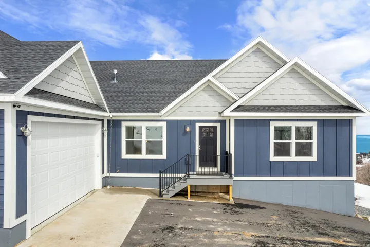 View of front facade featuring a shingled roof, concrete driveway, an attached garage, and board and batten siding