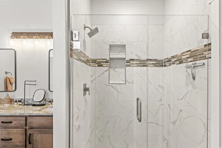 Full bath featuring vanity and a marble finish shower