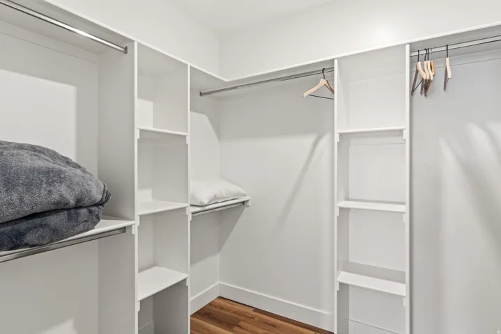 Walk in closet with dark wood finished floors