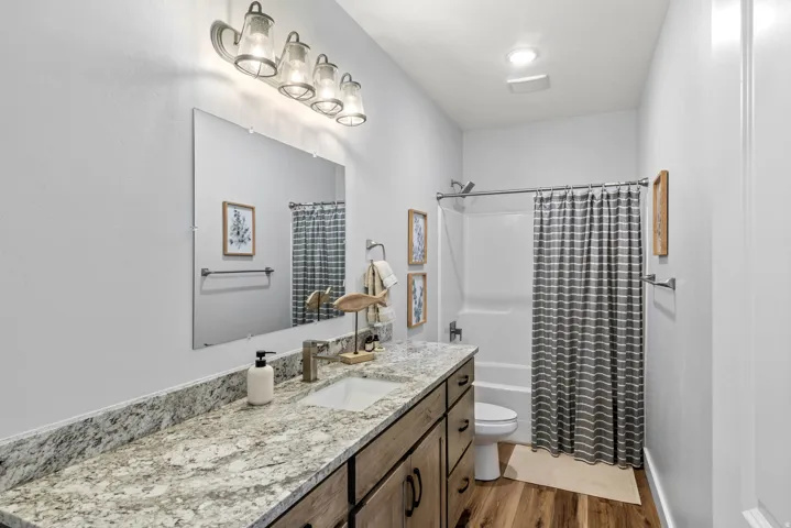 Full bathroom featuring vanity, shower / bath combo, and dark wood-style floors
