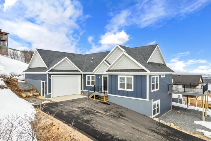 View of front of property featuring roof with shingles, board and batten siding, a garage, and asphalt driveway