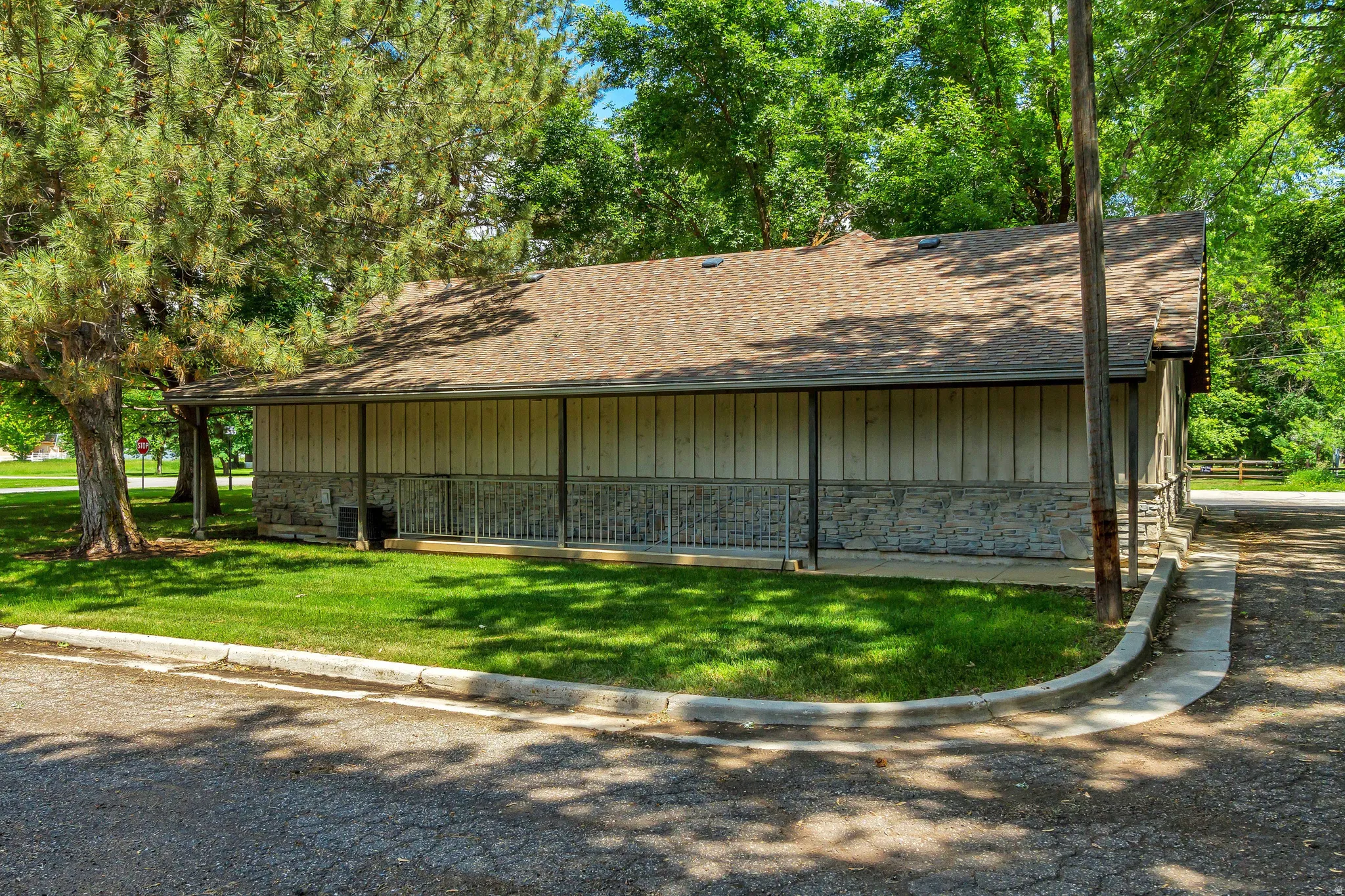 View of property exterior featuring roof with shingles, stone siding, a lawn, and board and batten siding