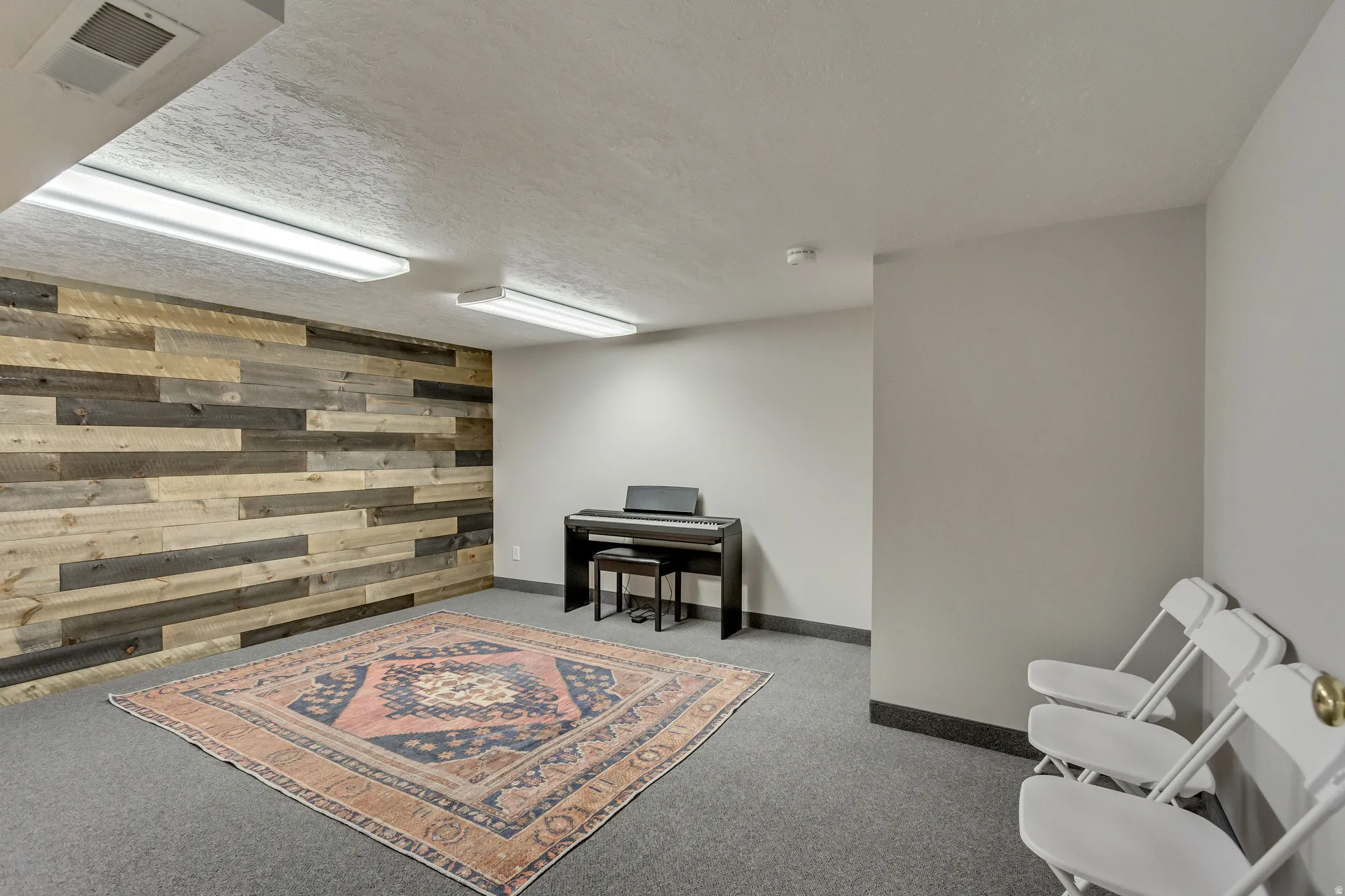 Sitting room with wooden walls, carpet floors, a textured ceiling, and an accent wall