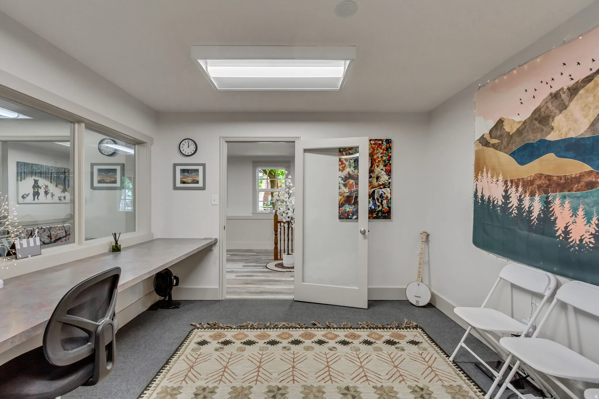 Office with dark colored carpet and baseboards