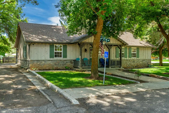 View of front of property featuring stone siding, roof with shingles, a porch, and board and batten siding