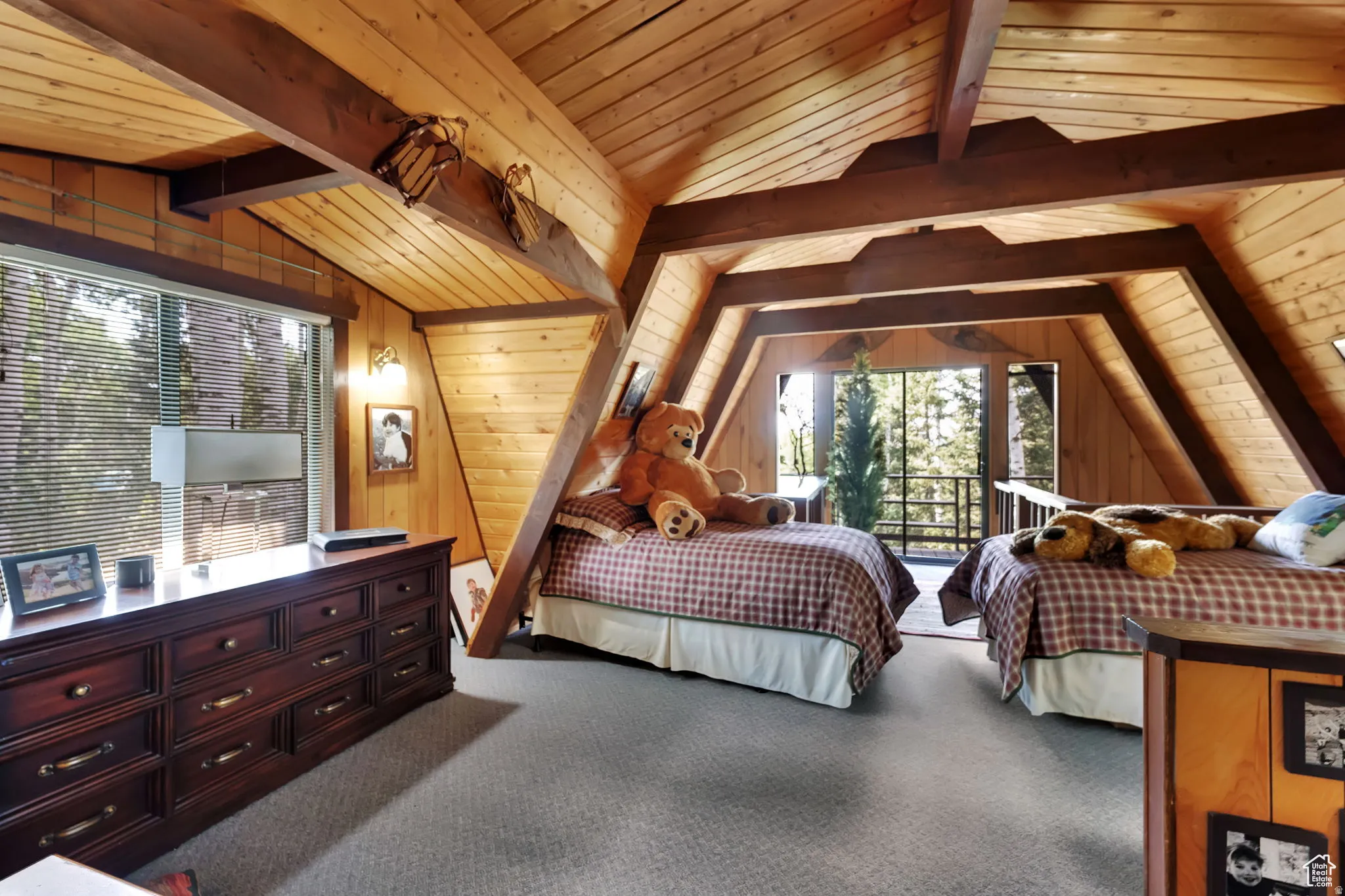 Carpeted bedroom with a wooden ceiling with exposed beams and access to outside