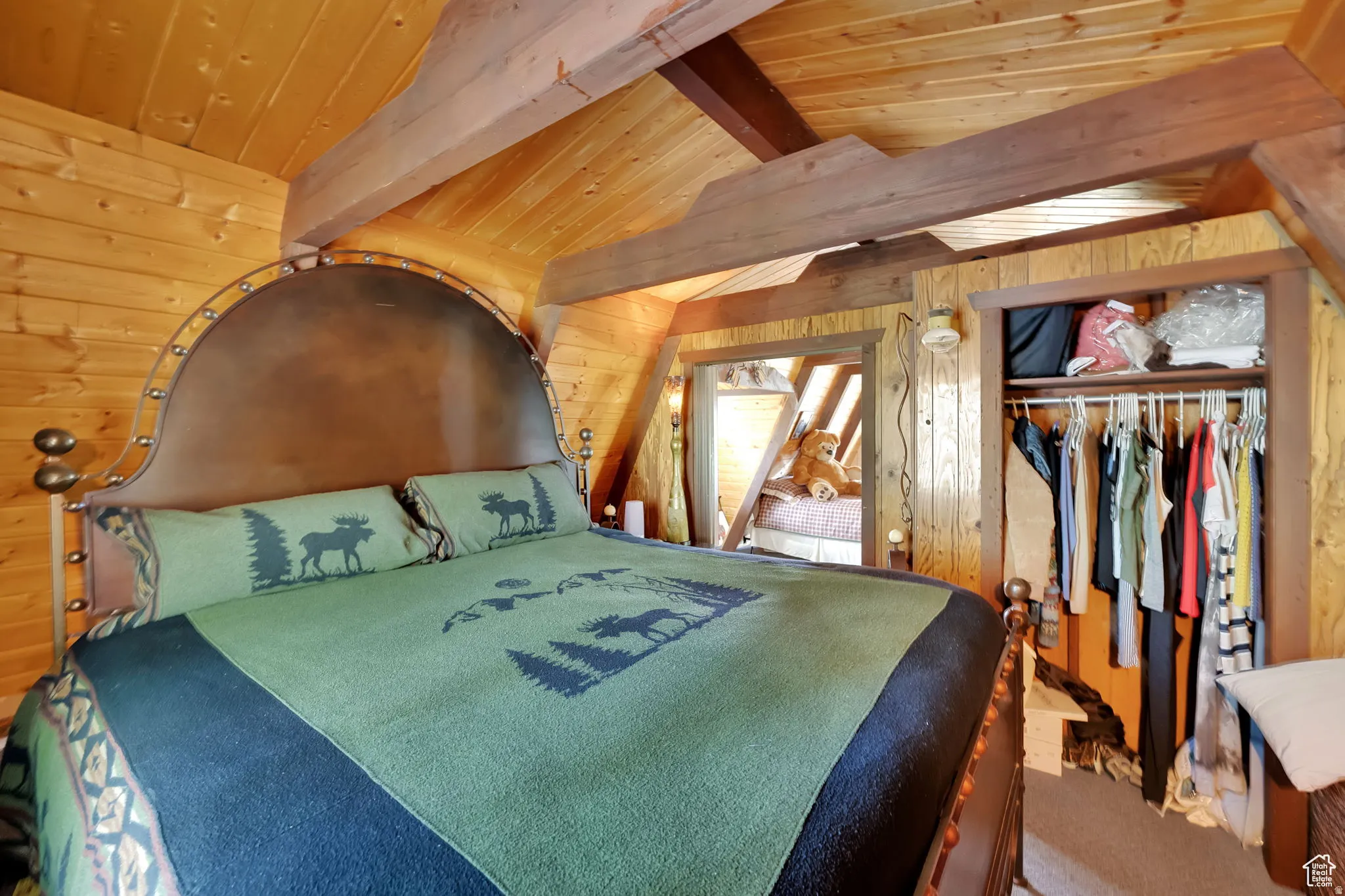 Bedroom with wood walls, vaulted ceiling with beams, wooden ceiling, and carpet
