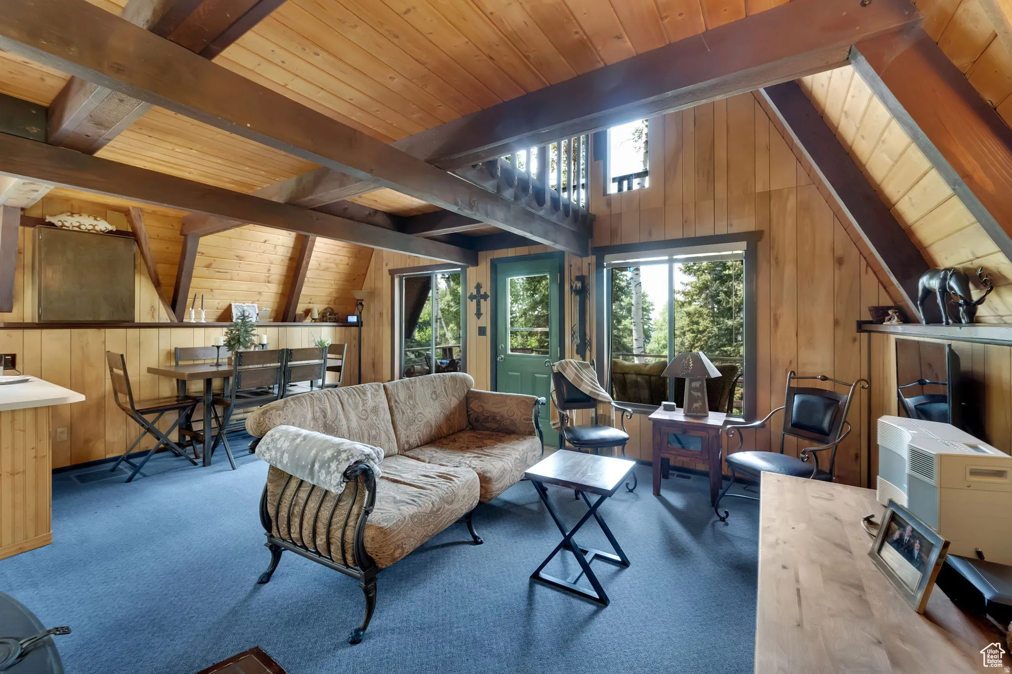 Carpeted living room with wood walls, wood ceiling, and lofted ceiling with beams