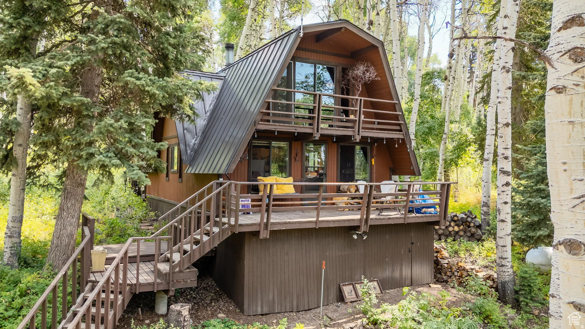Back of house featuring a deck, a metal roof, and a balcony