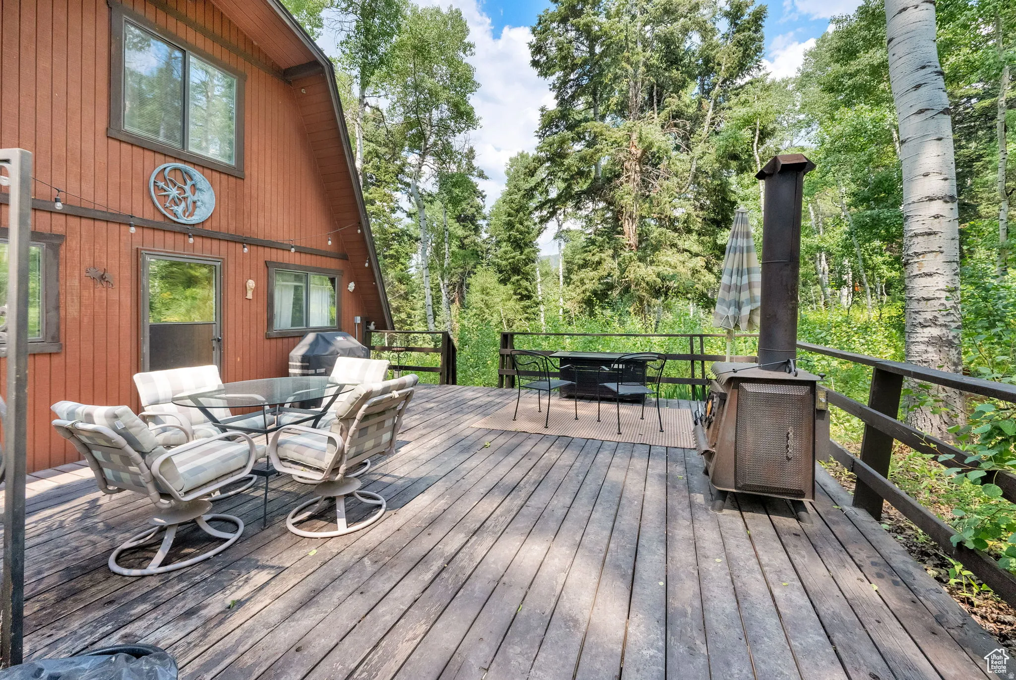 Deck featuring outdoor dining area, view of wooded area, and grilling area