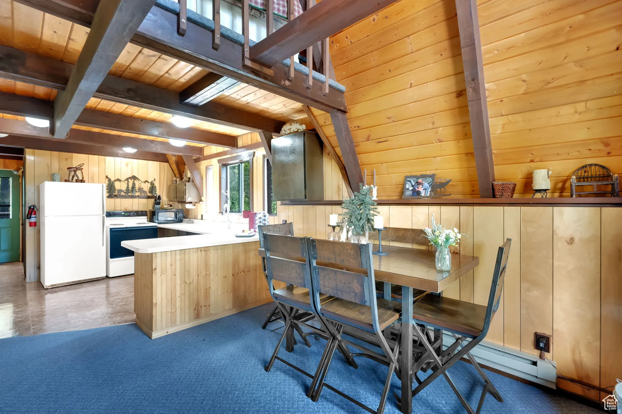 Kitchen featuring white appliances, a wooden ceiling with exposed beams, light countertops, a peninsula, and wooden walls