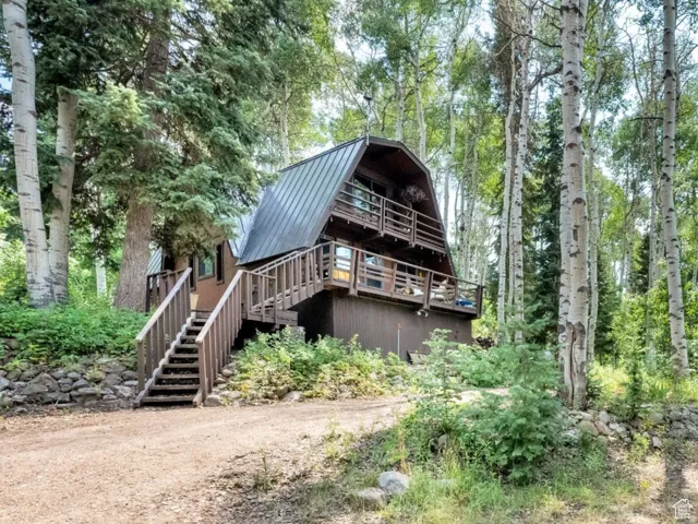 Rear view of property featuring a gambrel roof, a metal roof, and a deck