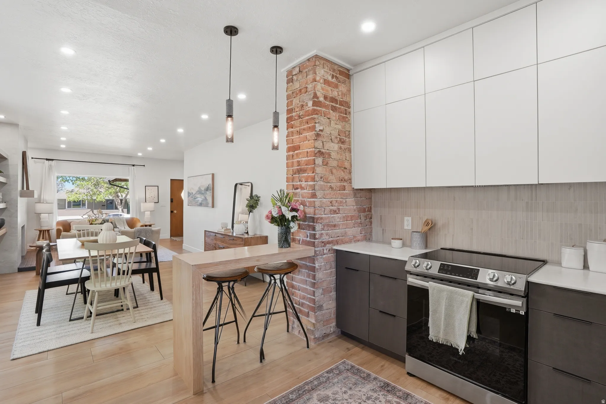 Kitchen with electric stove, marble countertops, pendant lighting, and open floor plan