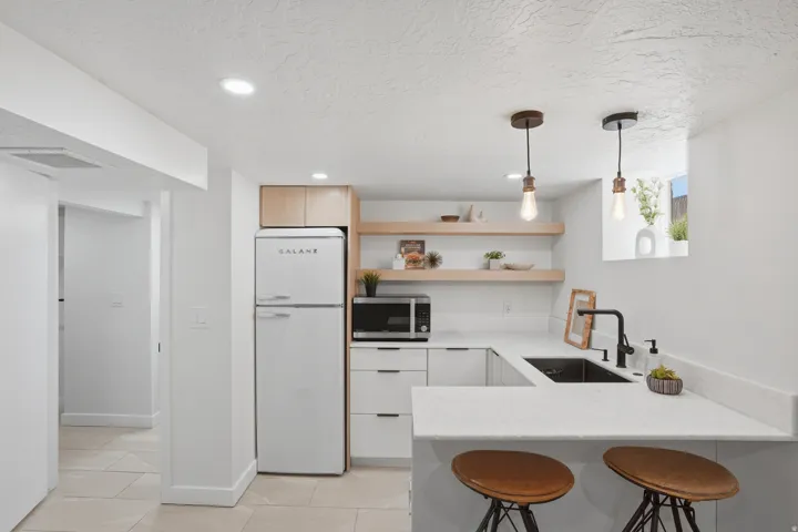 Kitchen with freestanding refrigerator, a peninsula kitchen breakfast bar, marble countertops and stainless steel microwave