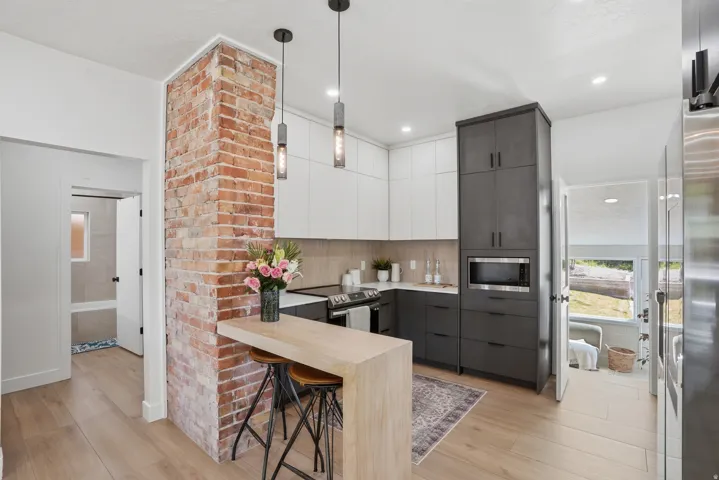 Kitchen featuring two tone color scheme, modern cabinets, pendant lighting, and a breakfast bar area