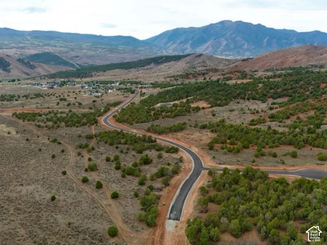 Expansive landscape featuring distant mountains, established community, and paved roads with cul-de-sac