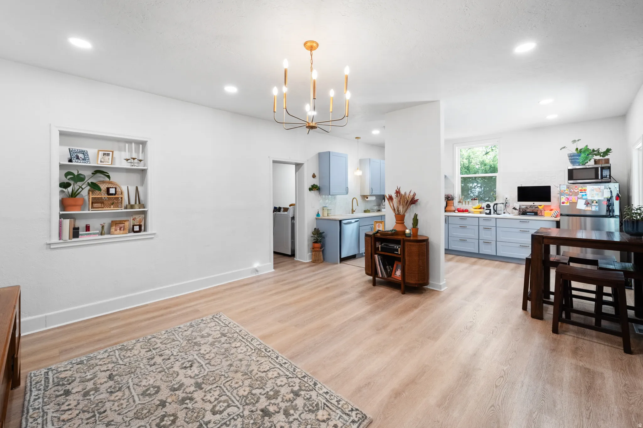 Kitchen featuring light countertops, hanging lights, light wood-style flooring, blue cabinets, and stainless steel appliances