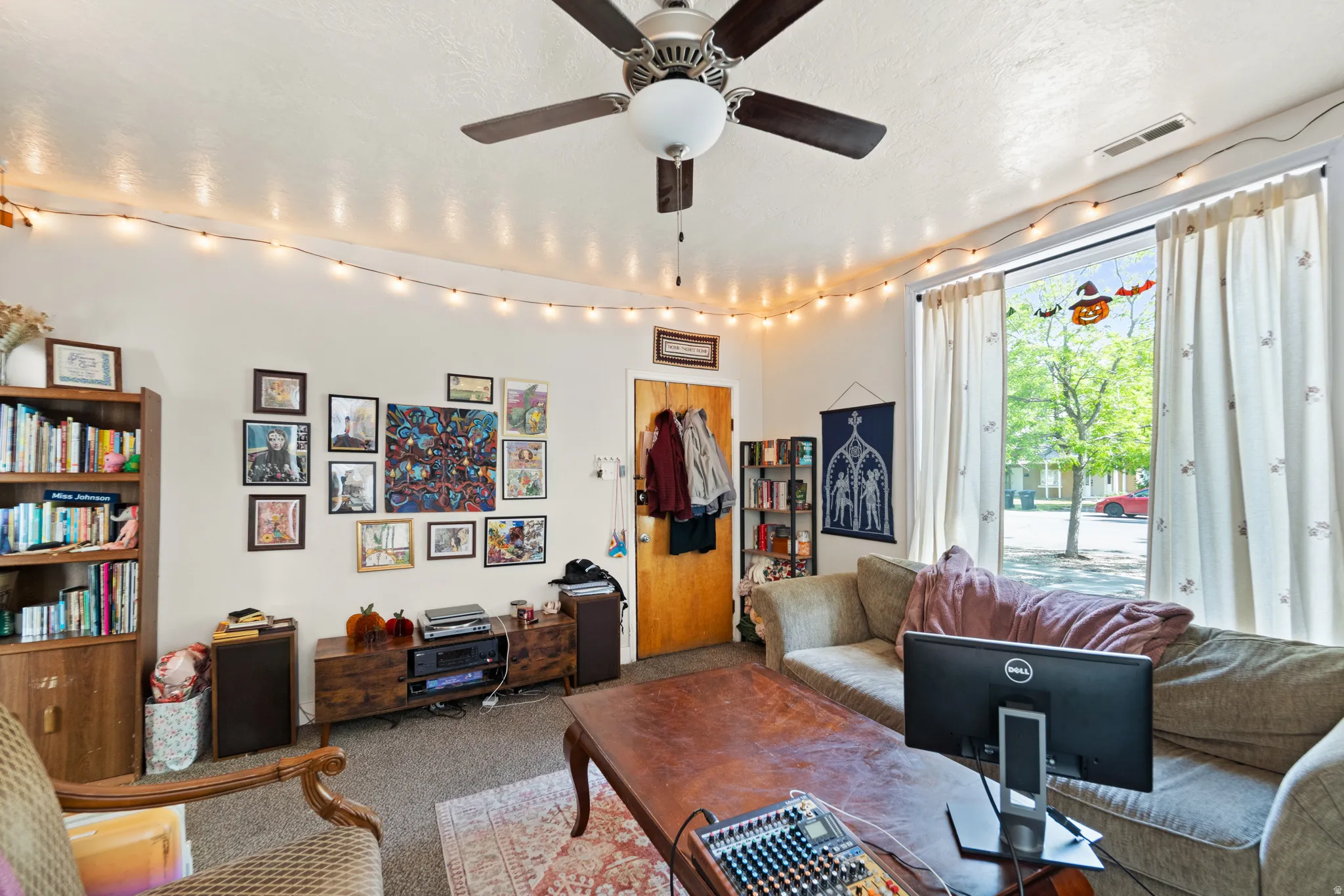 Carpeted living room with ceiling fan and a textured ceiling