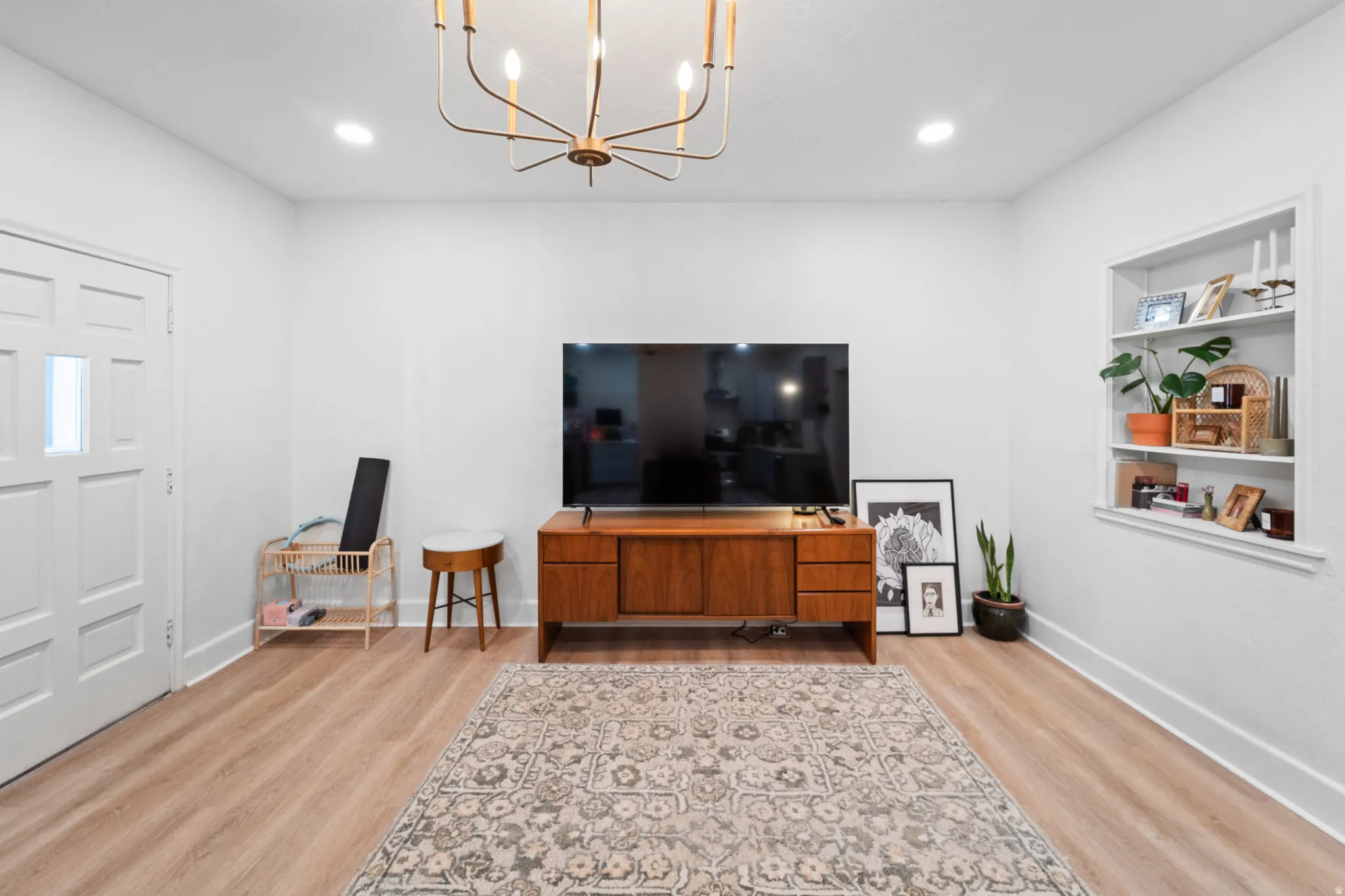 Living room featuring light wood finished floors, suspended lighting, and built in features