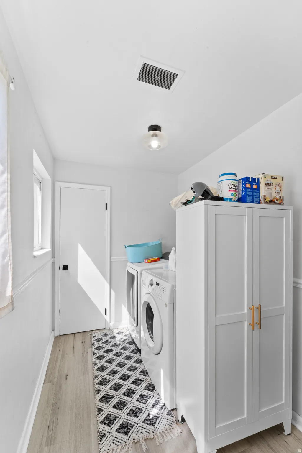 Laundry room with washer and dryer and light wood-type flooring