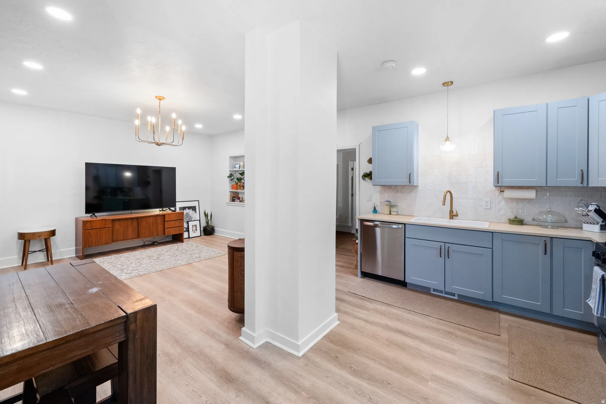 Kitchen featuring light wood-type flooring, stainless steel dishwasher, hanging lights, and blue cabinets