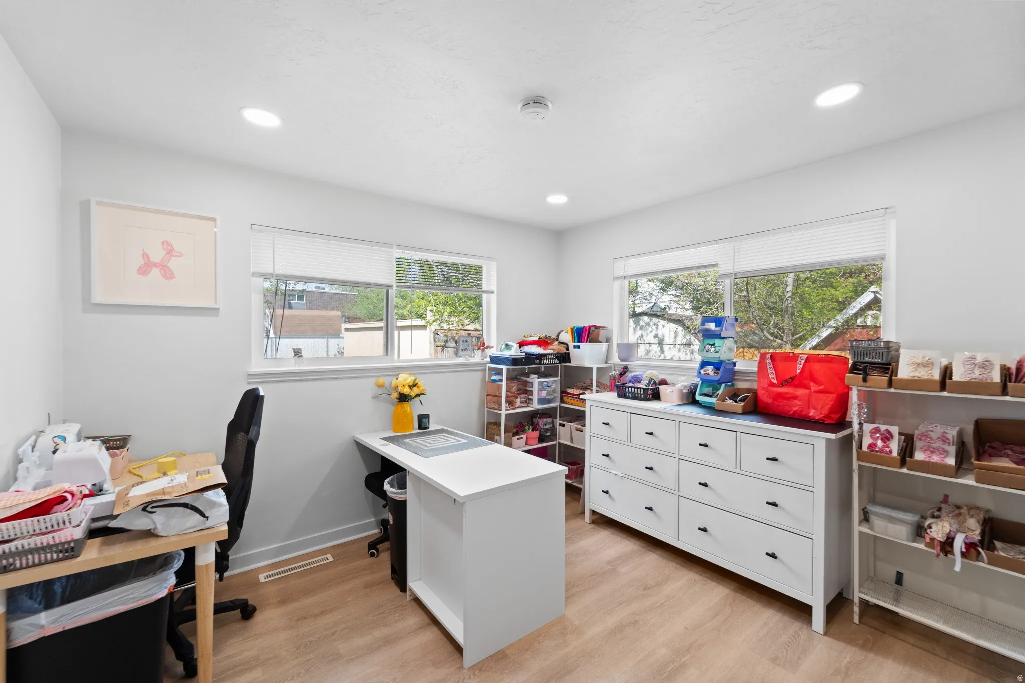 Home office with light wood finished floors and recessed lighting