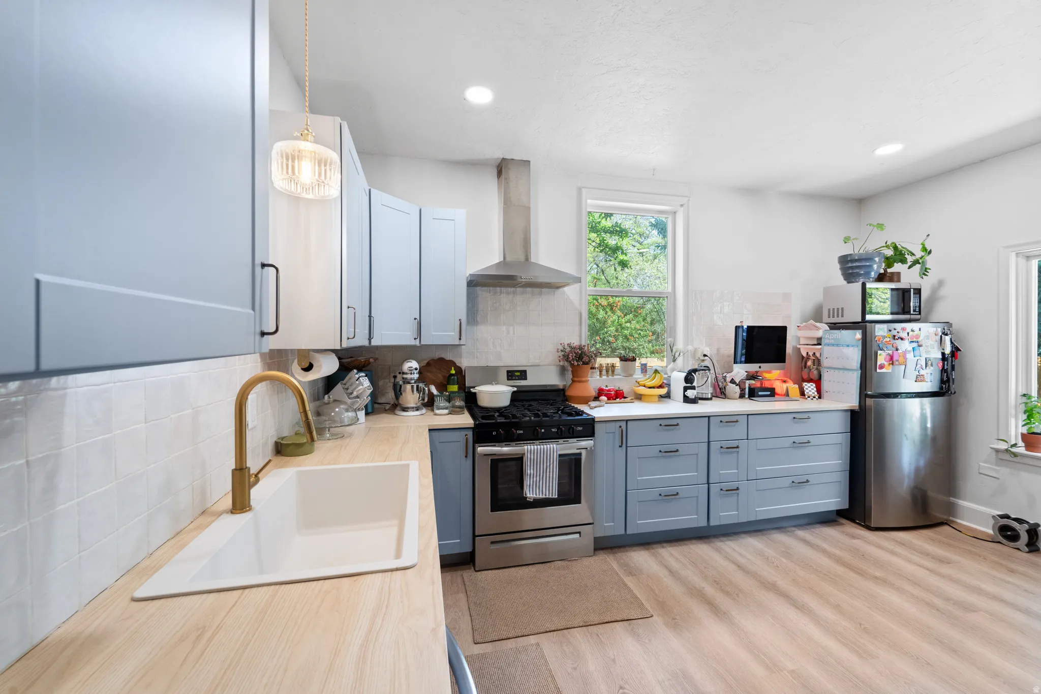 Kitchen with light countertops, stainless steel appliances, tasteful backsplash, light wood-style floors, and recessed lighting