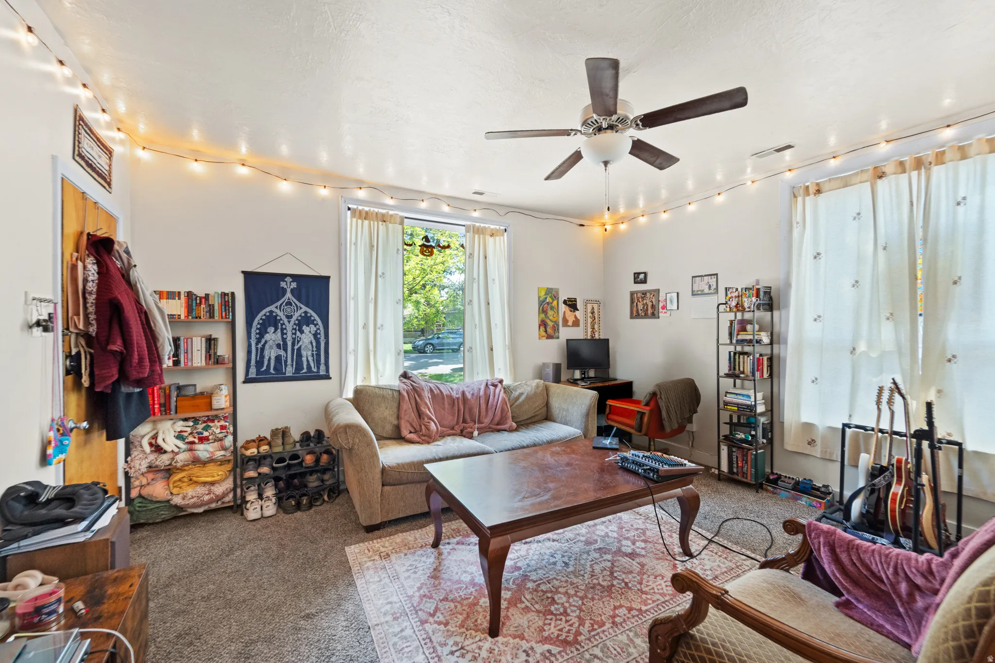 Carpeted living room featuring track lighting, ceiling fan, and a textured ceiling