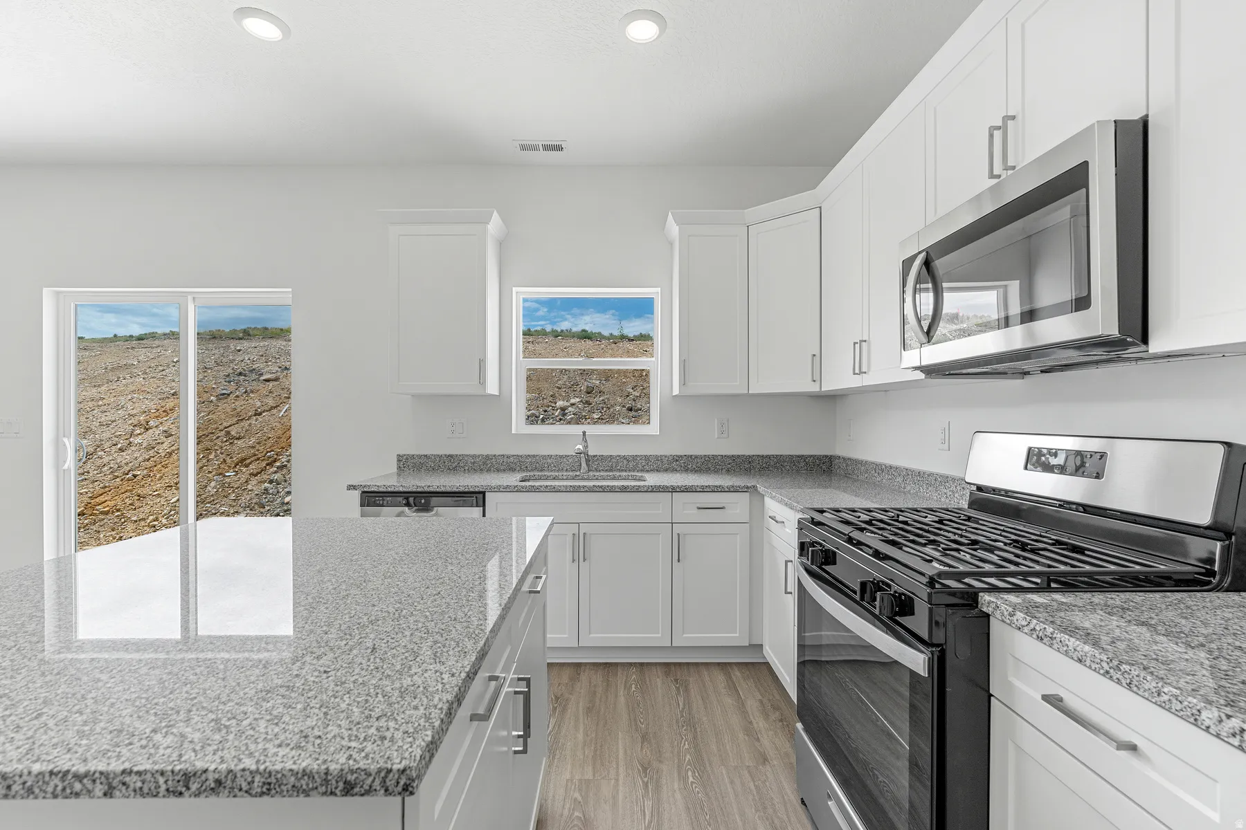 Kitchen featuring stainless steel appliances, white cabinetry, light stone countertops, light wood-type flooring, and recessed lighting
