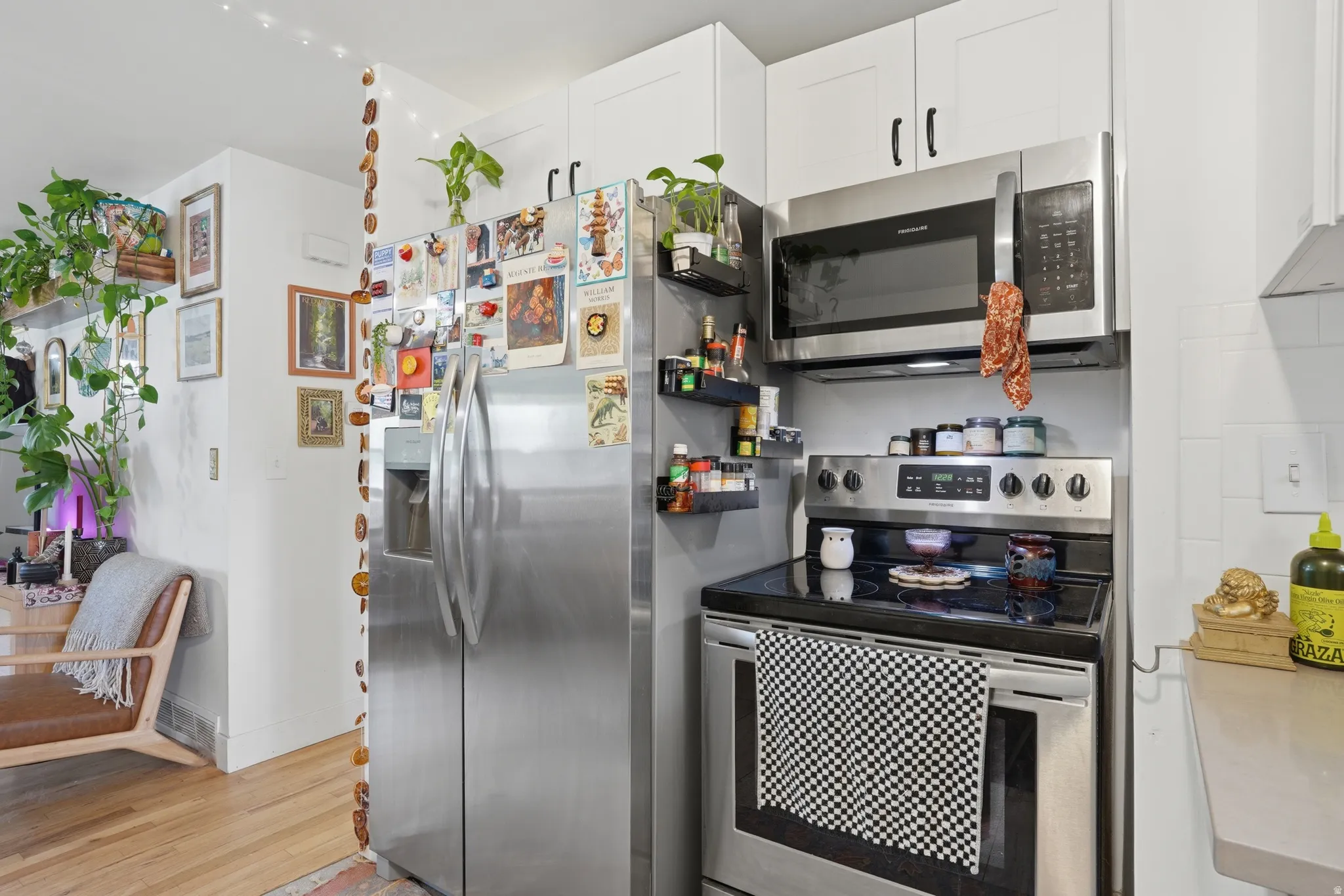Kitchen featuring stainless steel appliances, light wood finished floors, and white cabinetry