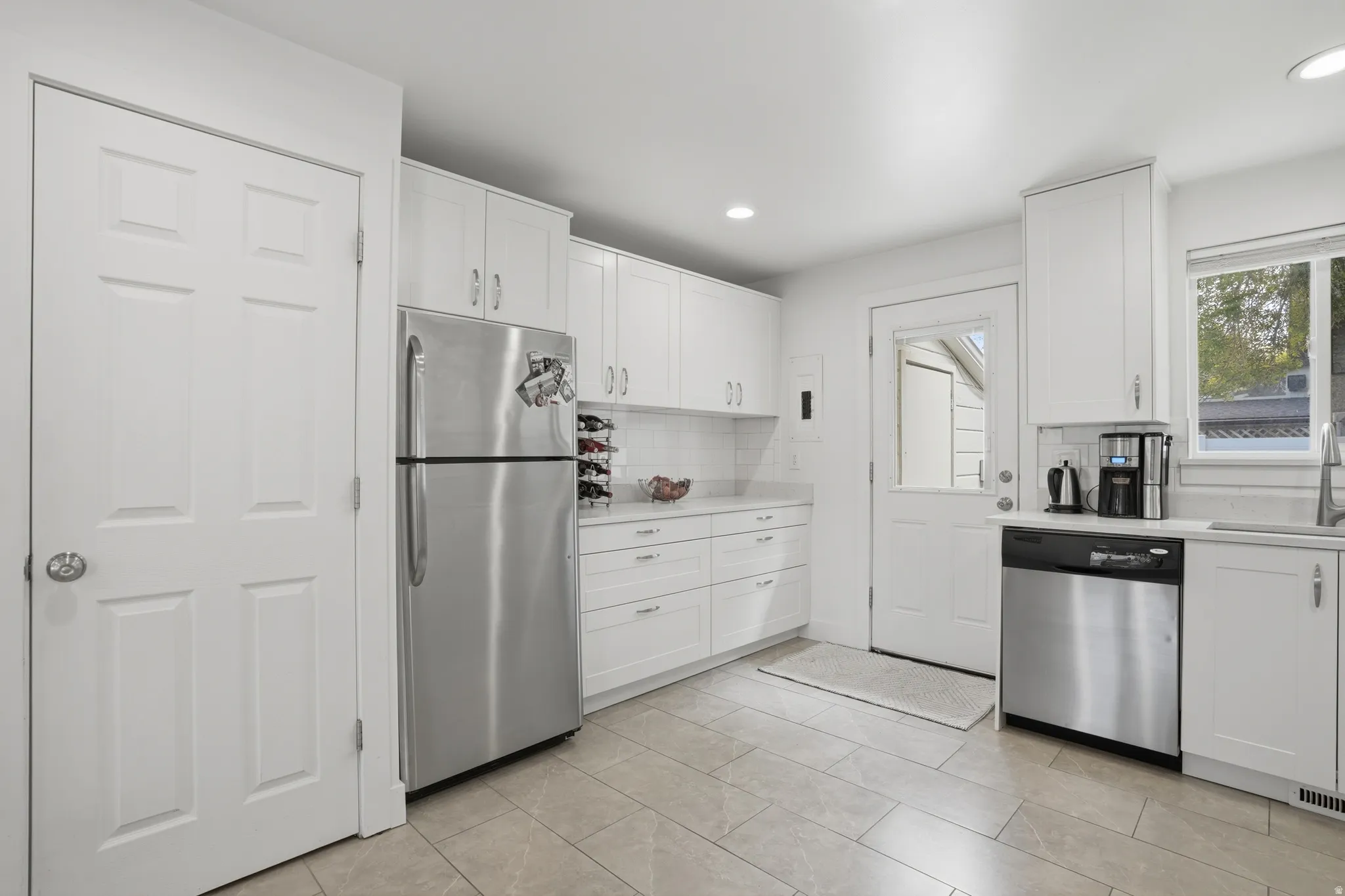 Kitchen with white cabinets, stainless steel appliances, backsplash, and recessed lighting